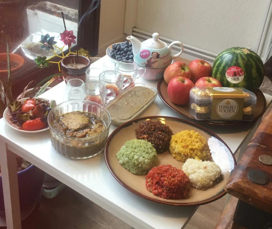 Mâm cúng Tết năm ngoái: xôi ngũ sắc, khay chè kho, một tô thức ăn, đĩa rau, ấm trà, ly nước, bát nhang, táo, dưa hấu và một hộp Ferrero Rocher.